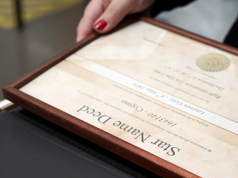 A close up of a framed certificate being put into a black box by a woman. The top of the certificate reads 